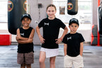Three kids in Team Teremoana caps and tees in the gym