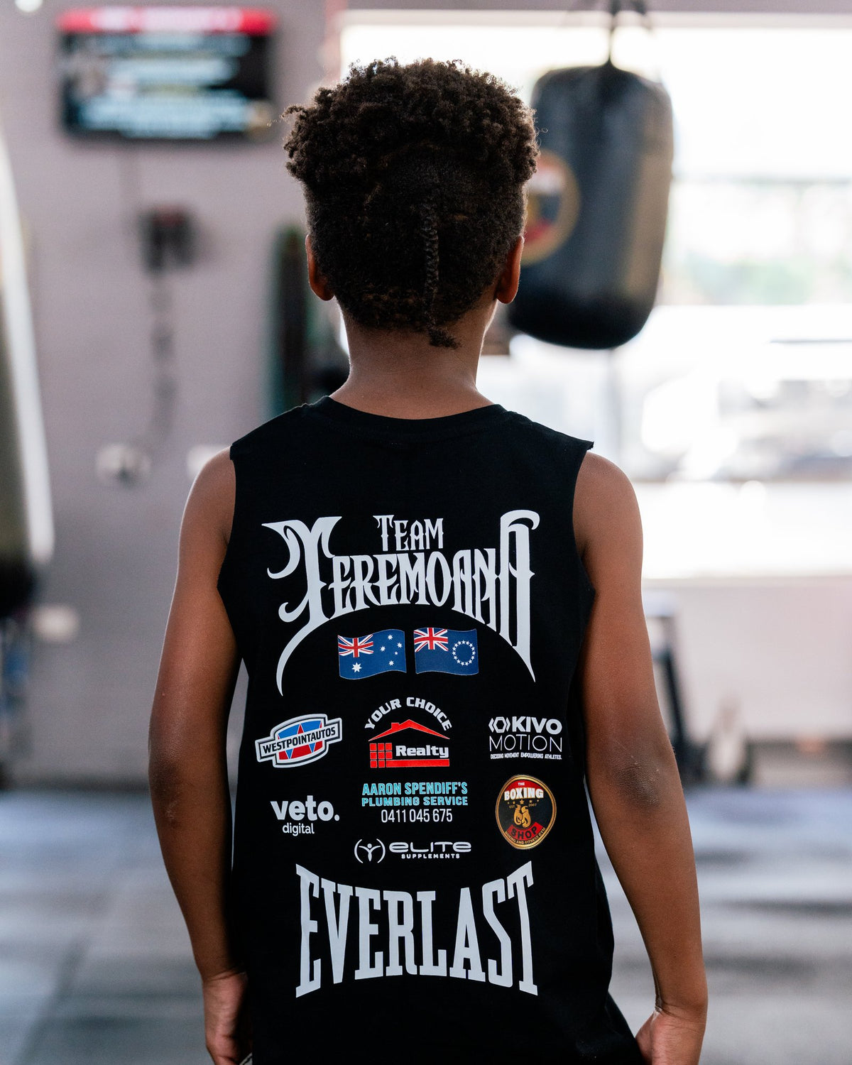 Back view of the kids black Team Teremoana Muscle Tank with the flags and sponsor print