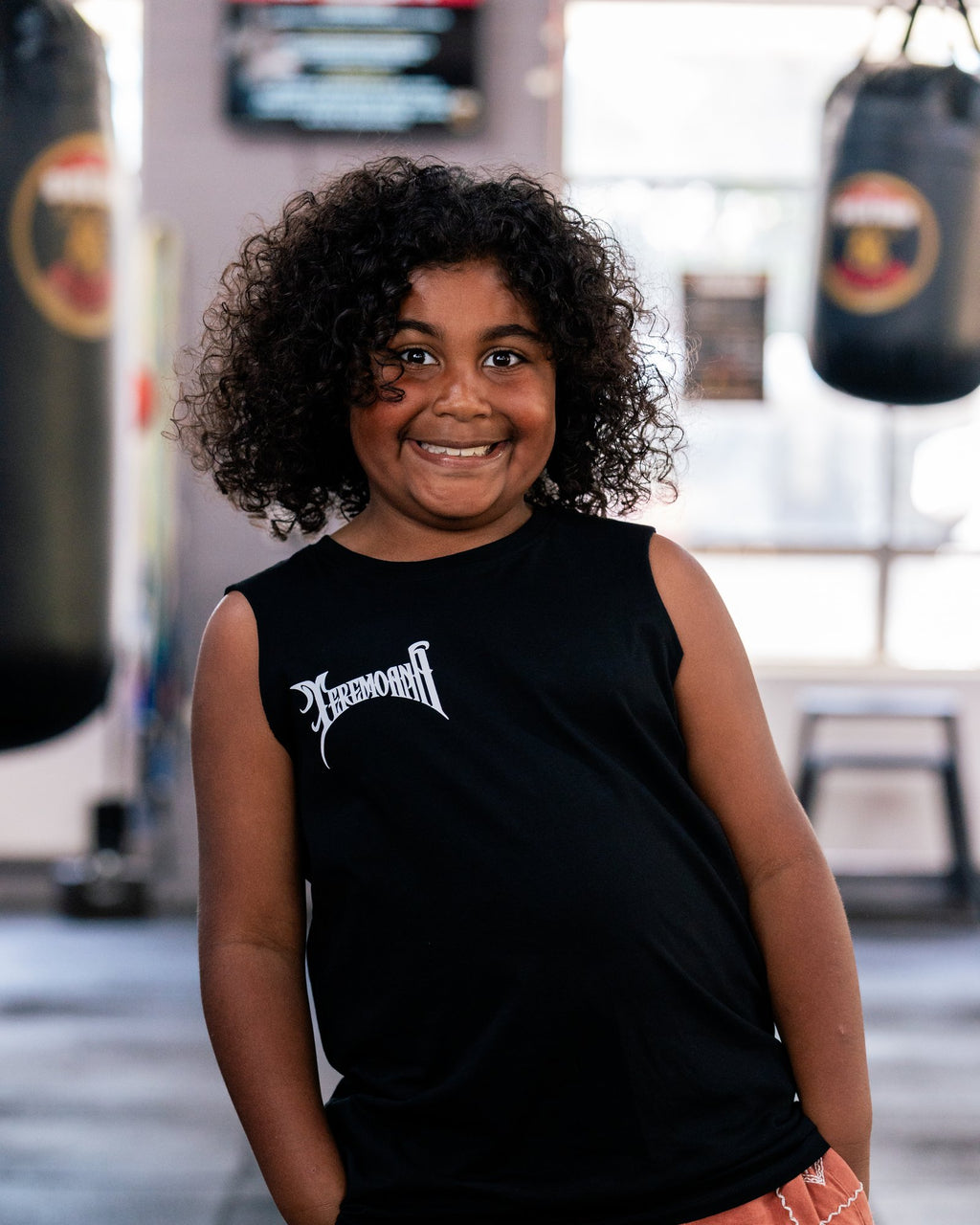 Child in the kids black Team Teremoana Muscle Tank in the gym, front view