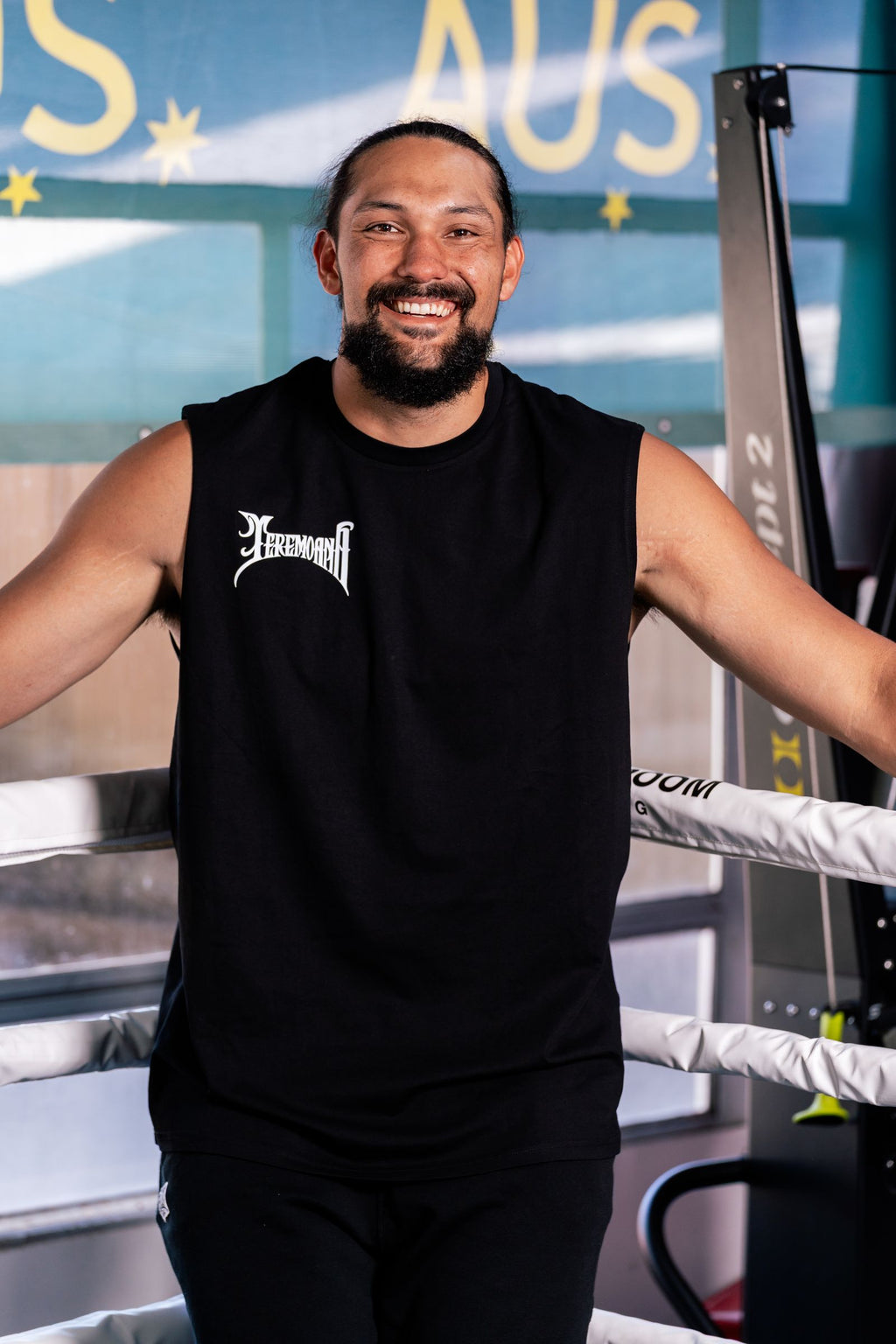 Teremoana smiling in the black Team Teremoana Muscle Tank, leaning on the ropes of the boxing ring