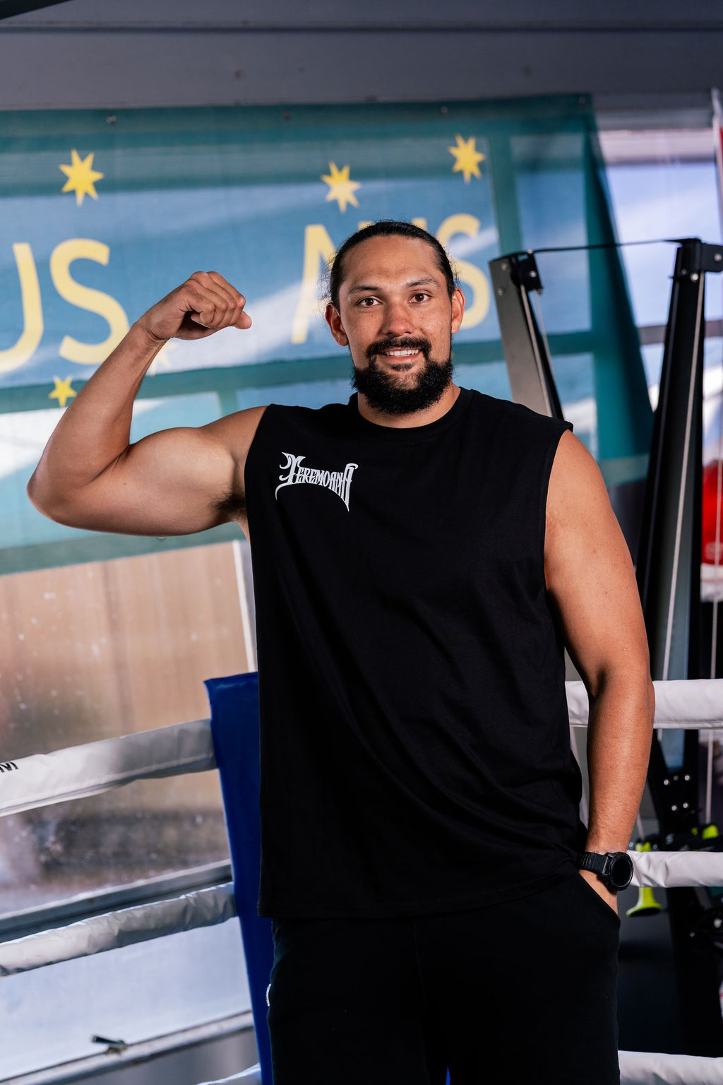Teremoana flexing in the black Team Teremoana Muscle Tank beside the boxing ring