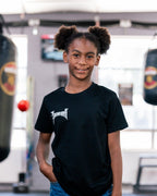 Smiling child in the kids black Team Teremoana Tee, front view